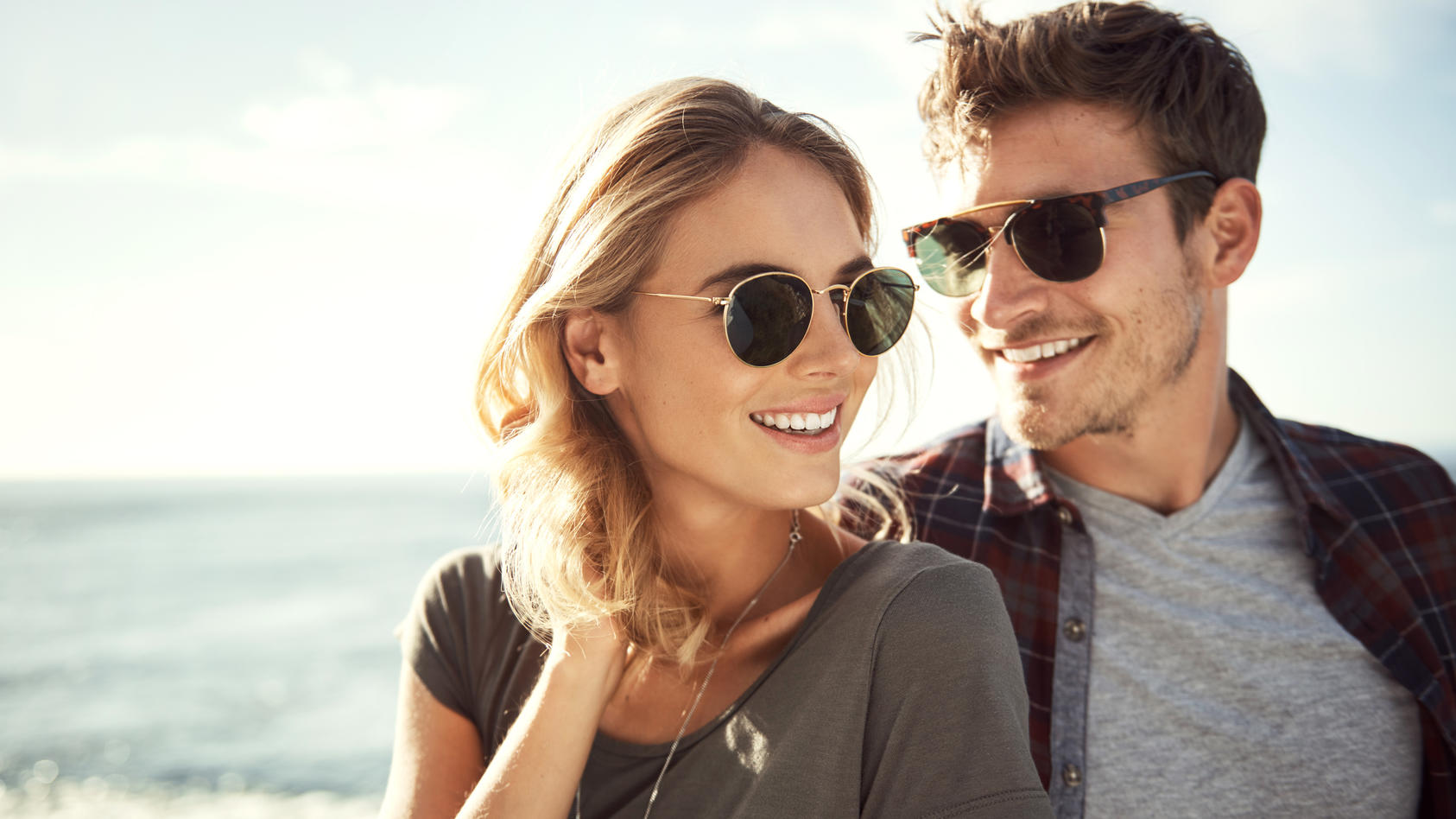 Frau und Mann tragen Sonnenbrillen und lachen.