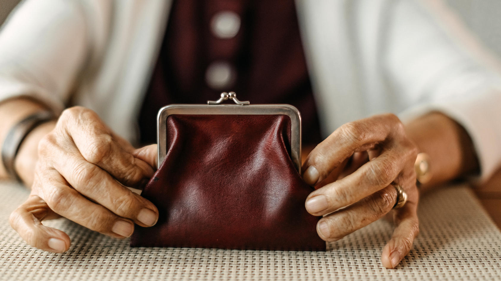 Eine Seniorin hält ein kleines Portemonnaie in den Händen.