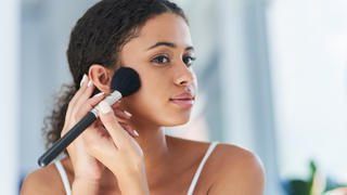 Eine Frau steht vor einem Spiegel und schminkt sich.