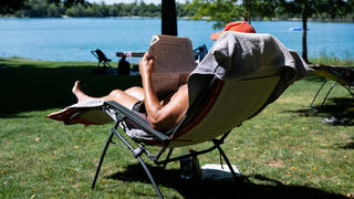 14.07.2022, Bayern, Eching: Ein Mann genießt das hochsommerliche Wetter in seinem Liegestuhl am Echinger See und liest eine Zeitung. Foto: Sven Hoppe/dpa +++ dpa-Bildfunk +++