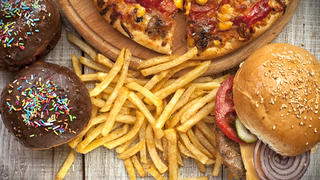 Closeup of home made burgers , french fries and donuts on wooden background