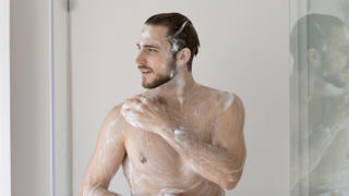 Mann seift Oberkörper mit Duschgel ein