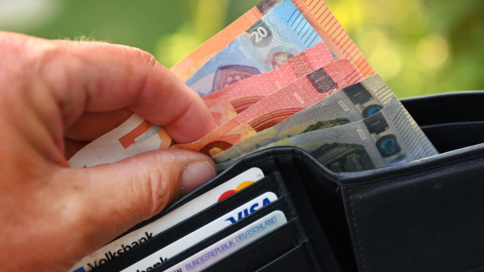 Eine Hand nimmt Geldscheine aus einem Portemonnaie
