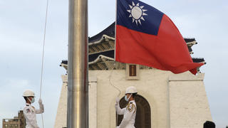 30.07.2022, Taiwan, Taipei: Zwei Soldaten senken die Nationalflagge während der täglichen Flaggenzeremonie auf dem Freiheitsplatz der Chiang Kai-shek Memorial Hall. (zu dpa: Nach Warnung aus China: Mögliche Taiwan-Reise Pelosis weiter offen) Foto: Chiang Ying-Ying/AP/dpa +++ dpa-Bildfunk +++