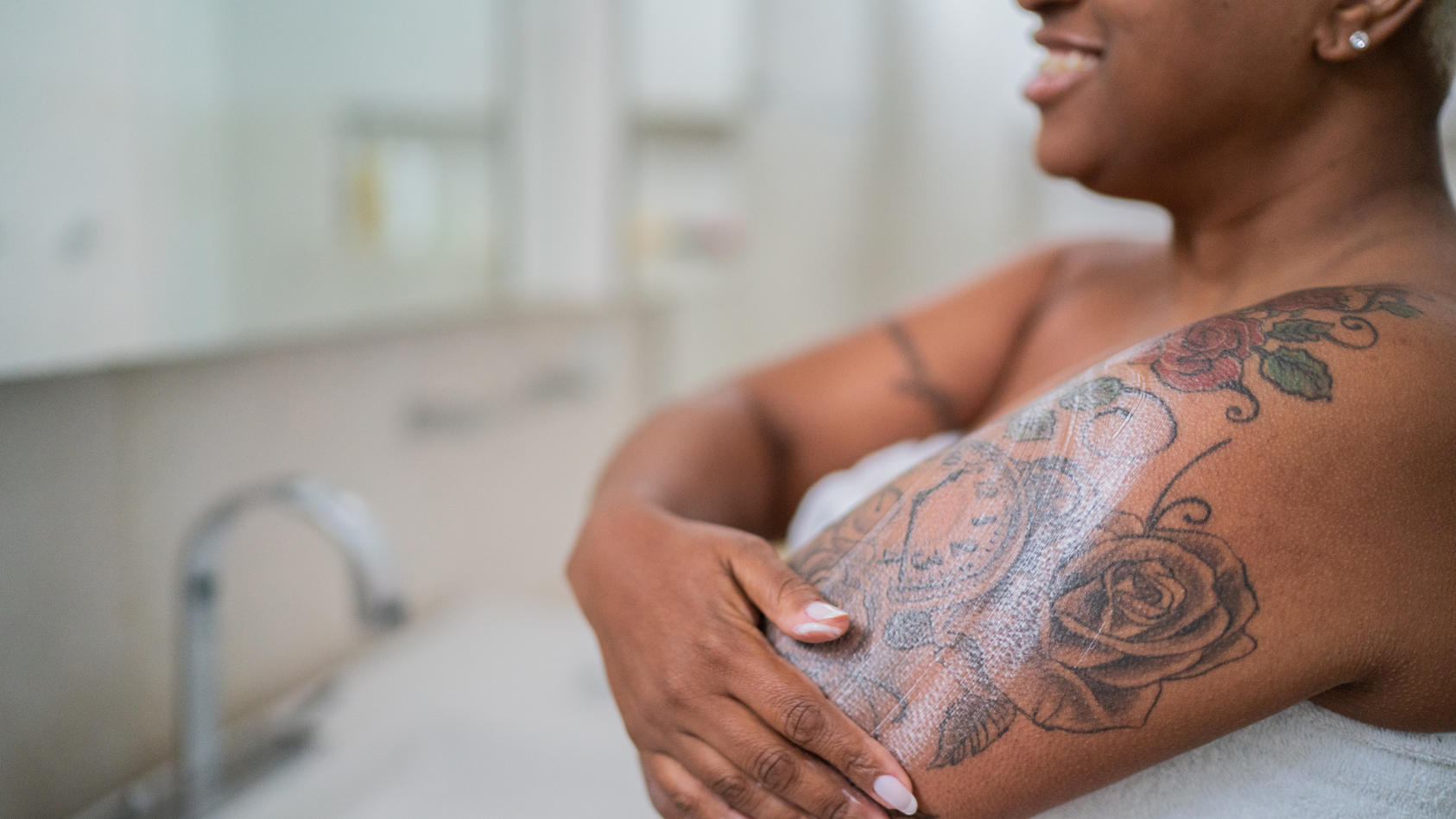 Eine Frau cremt ihr neu gestochenes Tattoo ein.