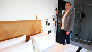 PRODUKTION - 08.08.2022, Niedersachsen, Braunlage: Meik Lindberg, Eigentümer des «The Hearts Hotel», stellt über ein Regelsystem die Temperatur in einem Hotelzimmer ein. Das Hotel kann die Ober- und Untergrenze der Temperatur zentral steuern. (zu dpa: «Pool, Heizung, Küche: Gastgewerbe sucht nach Energiesparmöglichkeiten») Foto: Stefan Rampfel/dpa +++ dpa-Bildfunk +++