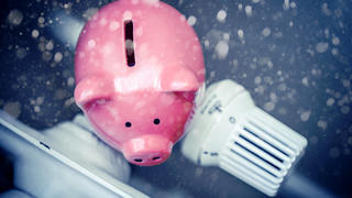  FOTOMONTAGE, Sparschwein auf Heizung bei Schneefall, Symbolfoto Energiesparen und steigende Heizkosten *** PHOTOMONTAGE, piggy bank on heater during snowfall, symbol photo energy saving and increasing heating costs.