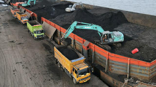 FILE PHOTO: A worker operates a heavy vehicle for unloading coal from the barge into a truck to be distributed, at the Karya Citra Nusantara port in North Jakarta, Indonesia, January 13, 2022. Picture taken with a drone, January 13, 2022. REUTERS/Willy Kurniawan/File Photo