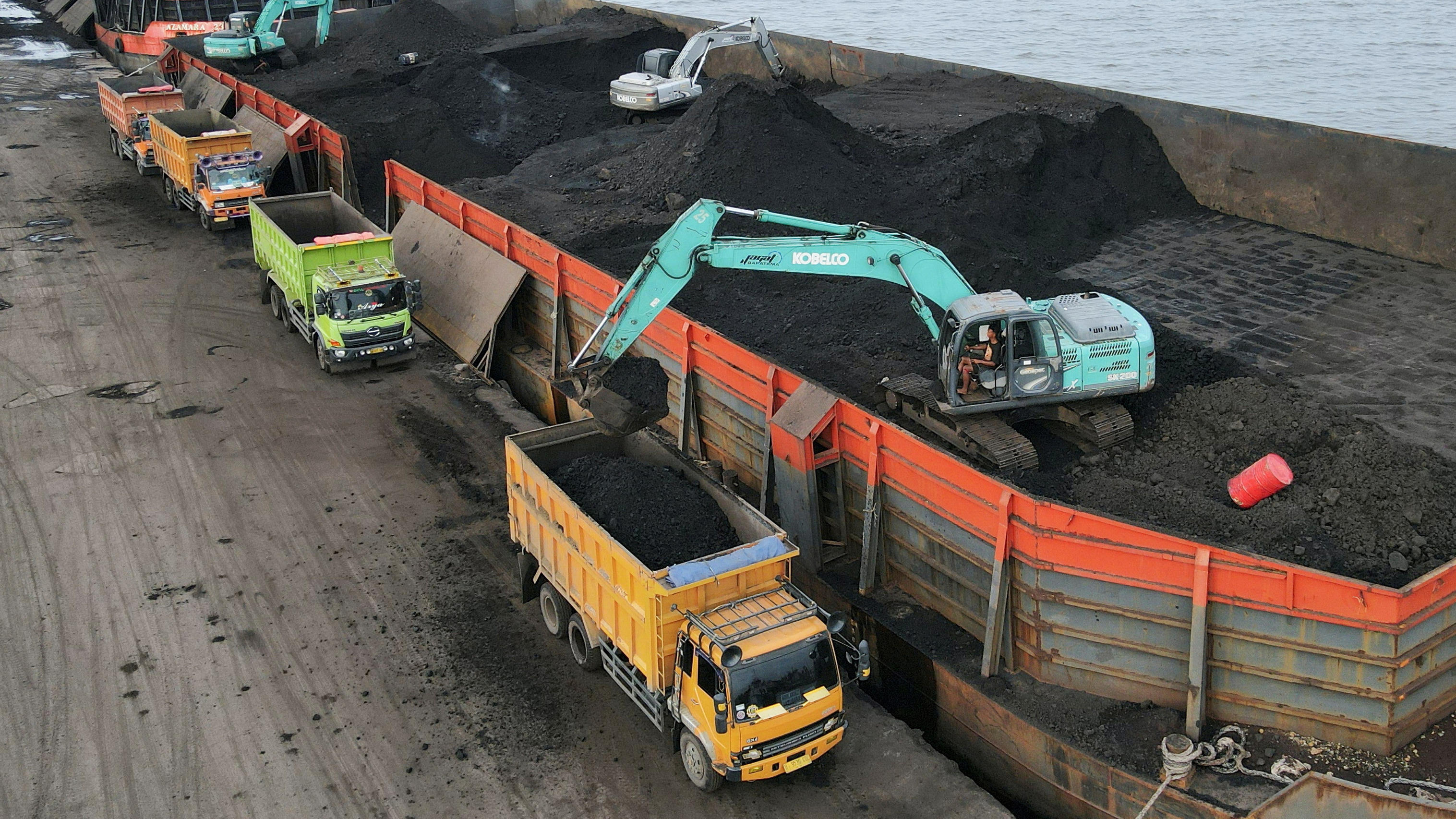 FILE PHOTO: A worker operates a heavy vehicle for unloading coal from the barge into a truck to be distributed, at the Karya Citra Nusantara port in North Jakarta, Indonesia, January 13, 2022. Picture taken with a drone, January 13, 2022. REUTERS/Wil