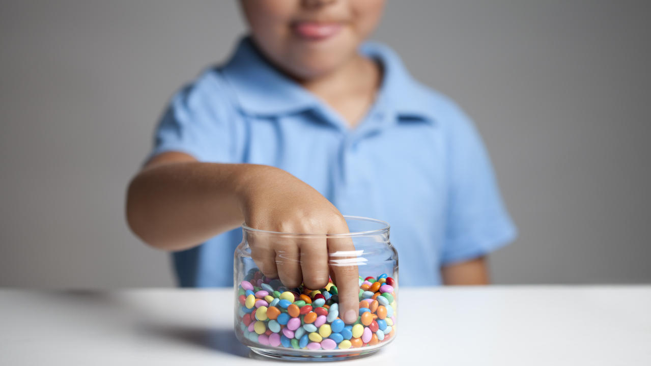 Kind greift im Süßigkeitenglas.