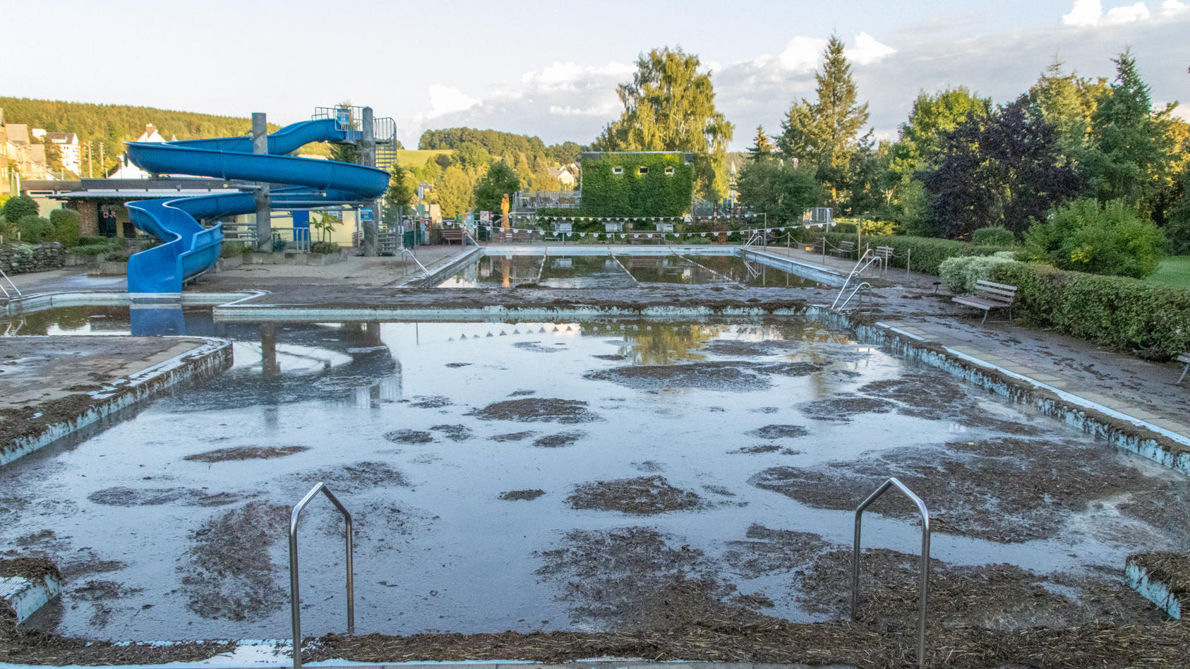 dpatopbilder - 06.09.2022, Sachsen, Burkhardtsdorf: Mit Schlamm ist ein Schwimmbecken in einem Freibad im Erzgebirge gefüllt. Nach Unwettern überrollte eine Schlammlawine das Freibad und spülte Schlamm und Geröll in die Schwimmerbecken. Die Freibad S