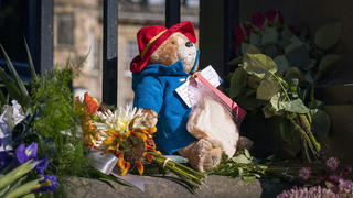 A Paddington Bear toy and marmalade sandwich is left amongst flowers and tributes outside the Palace of Holyroodhouse, following the death of Queen Elizabeth II on Thursday, in Edinburgh, Saturday, Sept. 10, 2022. Queen Elizabeth II, Britain's longest-reigning monarch and a rock of stability across much of a turbulent century, died Thursday after 70 years on the throne. She was 96. (Jane Barlow/PA via AP)
