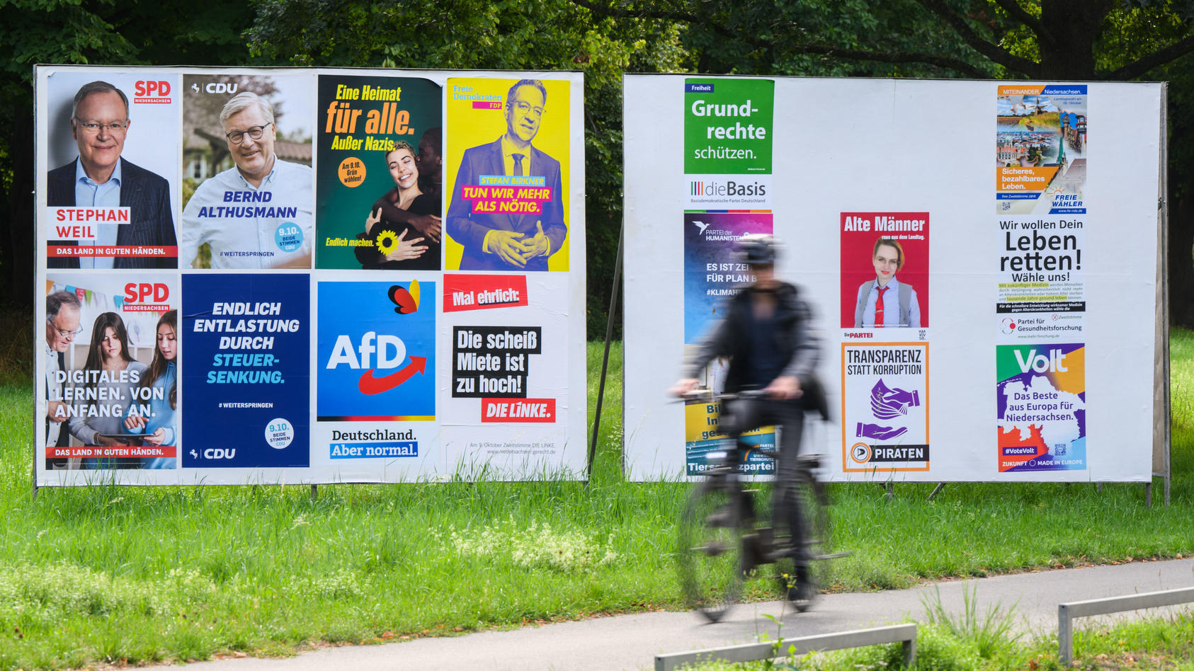 Ein Radfahrer radelt an einer Wand mit Wahlplakaten verschiedener Parteien vorbei.