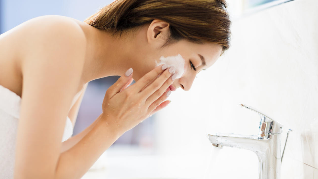 Frau wäscht Gesicht mit Reinigungsmilch