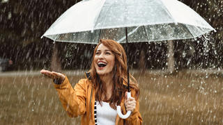 Frau freut sich über robusten Regenschirm.
