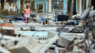 Ana Kapel walks through what is left of the Times Square area near the Lynn Hall Pier on the island of Fort Myers Beach, Fla., Friday, Sept. 30, 2022. Hurricane Ian made landfall Wednesday, Sept. 28, 2022, as a Category 4 hurricane on the southwest coast of Florida. (Amy Beth Bennett/South Florida Sun-Sentinel via AP)