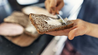 Ein Junge schmiert sich Butter auf sein Brot.