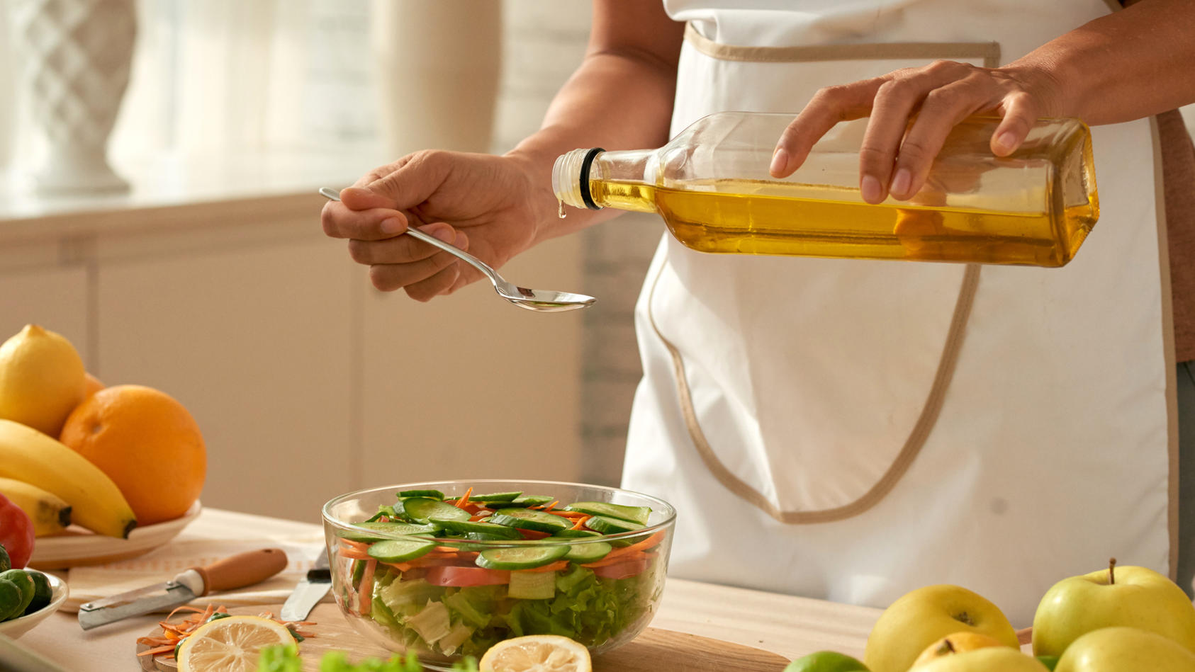 Frau träufelt Öl mit Löffel über Salat