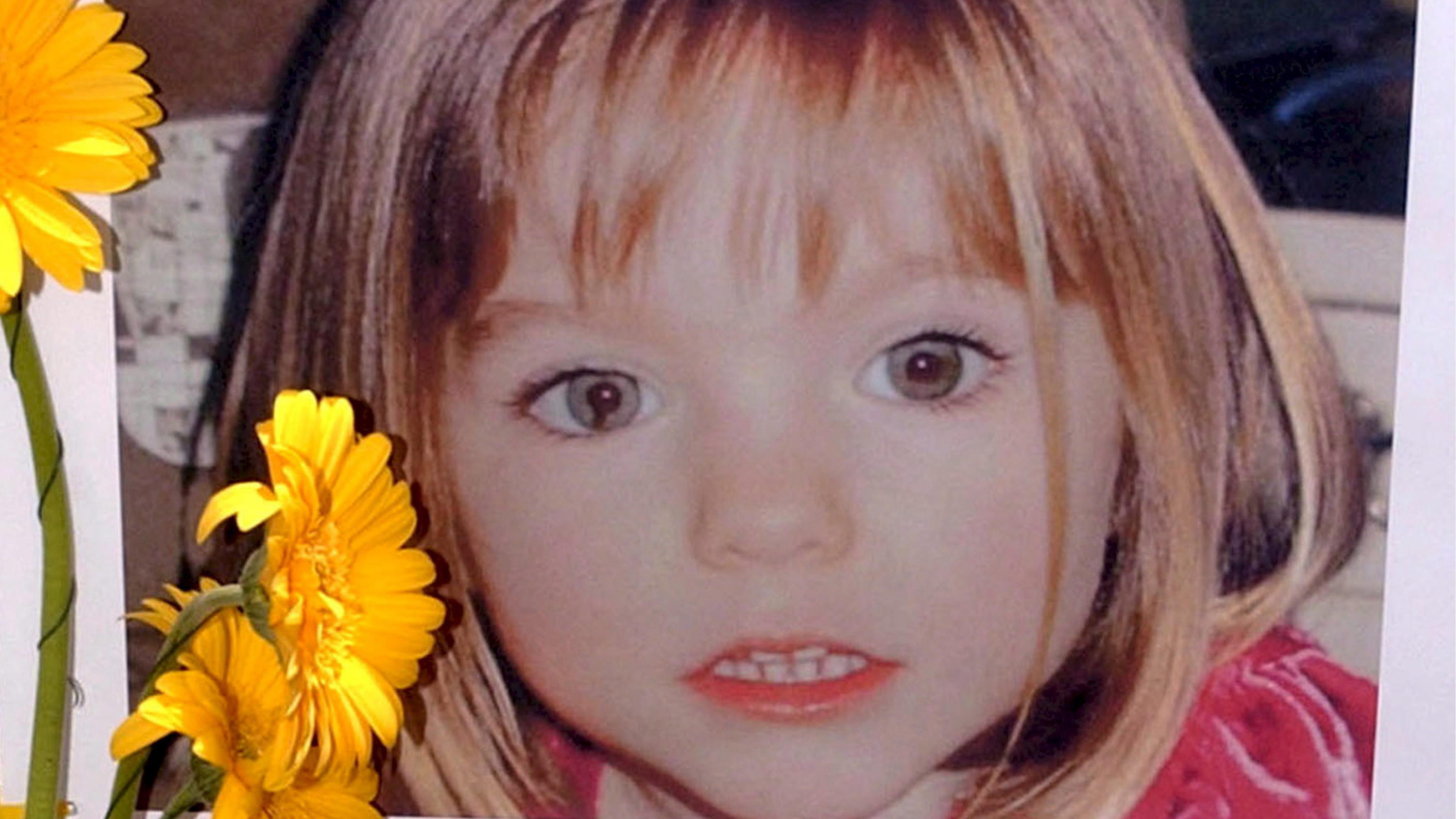ARCHIV - 12.05.2007, Portugal, Lagos: Blumen stehen vor einem Bild, das die verschwundene Madeleine McCann (Maddie) auf einem Foto zeigt, das ihre Eltern im Zusammenhang mit dem Verschwinden des Kindes veröffentlich haben. Am 3. Mai 2007 verschwand d