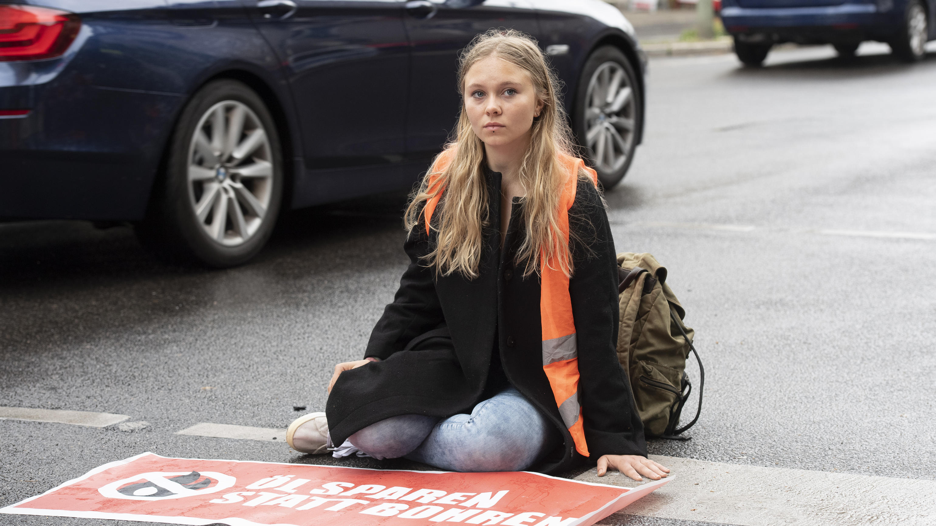 Klimaschutz-Demonstrantin Aimée van Baalen (22) sitzt unweit der Wetraße auf der Fahrbahn. Mitglieder der Gruppe "Letzte Generation" haben nach einer längeren Pause heute wieder zahlreiche Straßen in der Stadt blockiert.