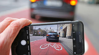 ILLUSTRATION - 16.04.2021, Nordrhein-Westfalen, Köln: ARCHIV - Auf einem Smartphone ist das Bild eines Autos zu sehen, das auf einem Radfahrstreifen hält. (zu dpa: «Prozess: Dürfen Bürger Falschparker für Anzeige fotografieren?») Foto: Oliver Berg/dpa - ACHTUNG: Kfz-Kennzeichen wurde aus persönlichkeitsrechtlichen Gründen gepixelt +++ dpa-Bildfunk +++