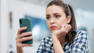Frau schaut verwirrt ins Handy