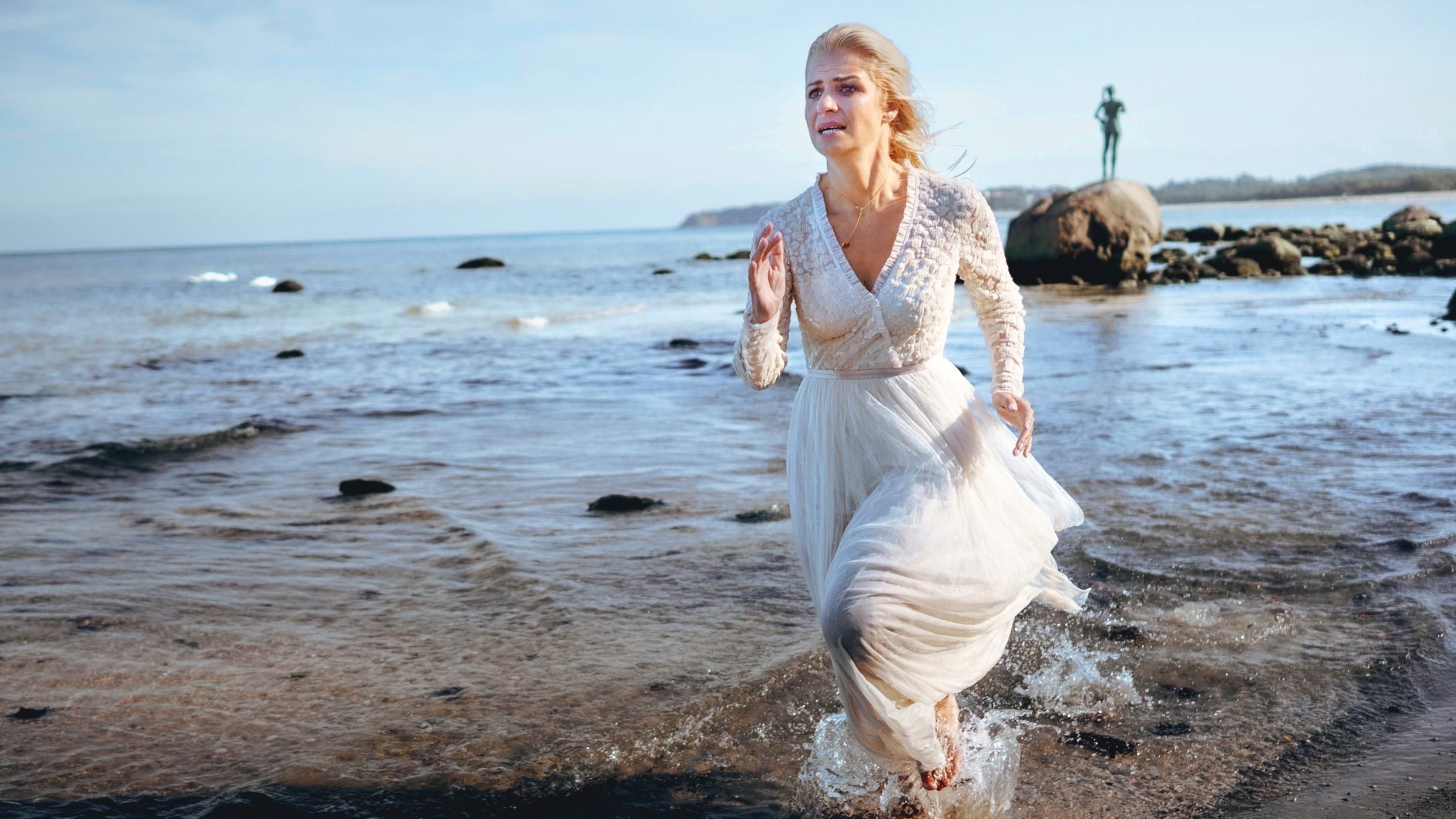 Sarah (Susan Sideropoulos) rennt im Hochzeitskleid am Strand entlang. Was hast das zu bedeuten? 