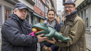Britta Schatton und Dirk Büttner (rechts) übergeben den gefundenen Froschkönig an Marktmeister Sven Kaestner. Quelle: Stadt Erfurt