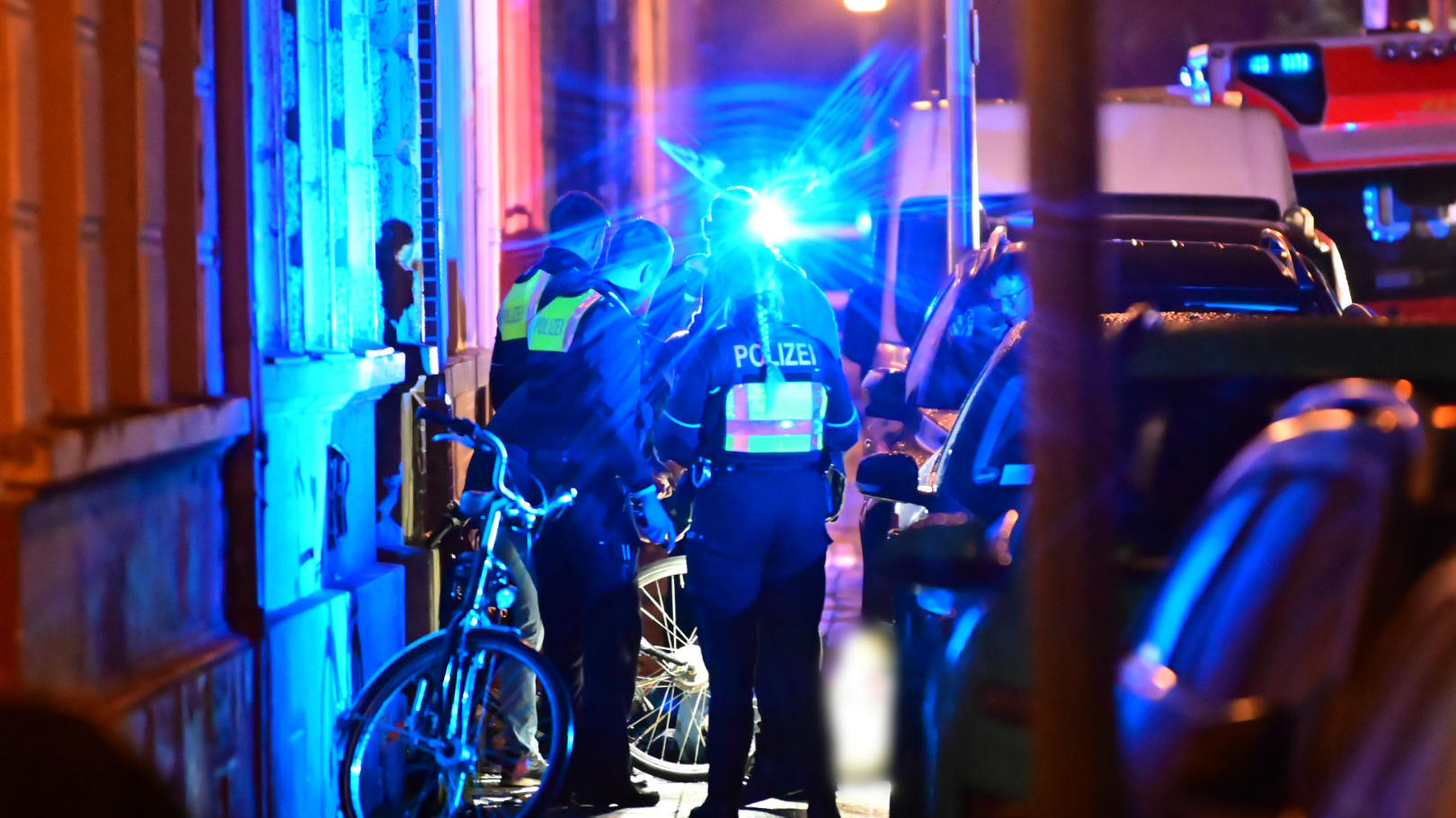 28.11.2022, Nordrhein-Westfalen, Krefeld: Polizisten stehen auf einem Geweg neben dem Toten. In der Krefelder Innenstadt ist am Montagabend ein Mann auf offener Straße erschossen worden. «Es gab eine Schussabgabe auf der Garnstraße. Eine Person ist v
