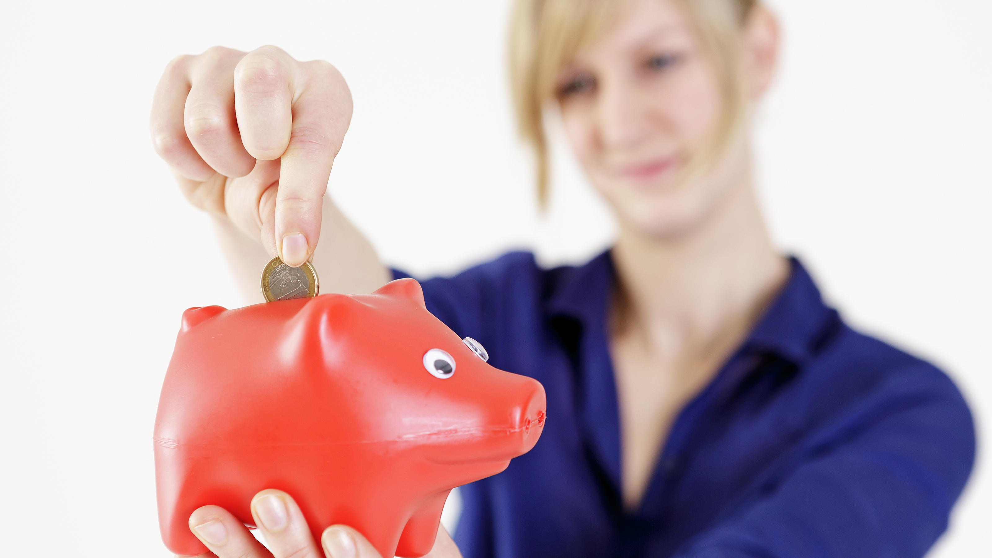 A woman puts a coin in a piggy bank to save money. 