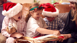 Kinder packen Weihnachtsgeschenke aus und freuen sich