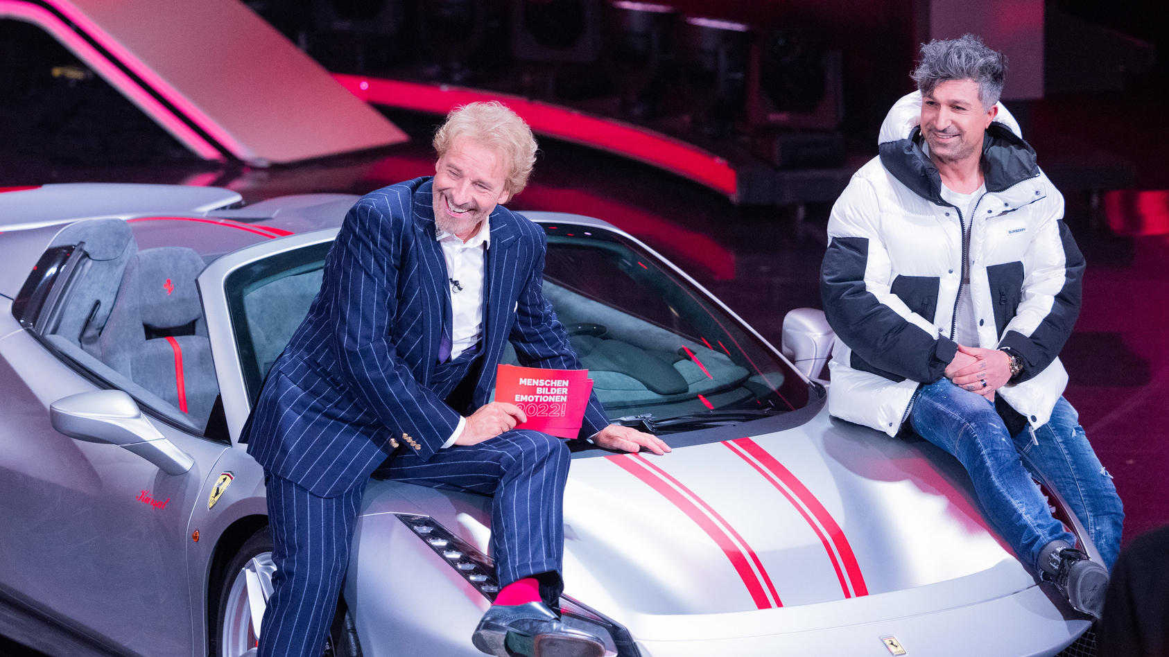 11.12.2022, Nordrhein-Westfalen, Hürth: Thomas Gottschalk (l), Moderator, und  Lotto-Millionär Kürsat Yildirim alias "Chico" sitzen auf einem Ferrari beim RTL-Jahresrückblick "Menschen, Bilder, Emotionen 2022" im Studio. Foto: Rolf Vennenbernd/dpa ++