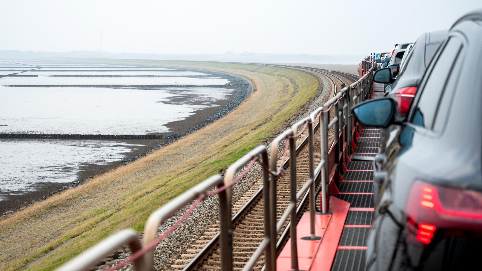 PRODUKTION - 30.11.2022, Schleswig-Holstein, Klanxbüll / Sylt: Ein Autozug der Deutschen Bahn fährt über den Hindenburgdamm auf die Nordseeinsel Sylt. In regelmäßigen Abständen flammt alle Jahre wieder die Debatte um eine Umbenennung des Bahndammes n