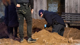 12.12.2022, Schleswig-Holstein, Alt Mölln: Ermittler der Polizei arbeiten hinter einem Mehrfamilienhaus in einem Garten an einem Erdloch. Dort wurde am Mittag eine vergrabene Leiche gefunden. Foto: Daniel Bockwoldt/dpa +++ dpa-Bildfunk +++