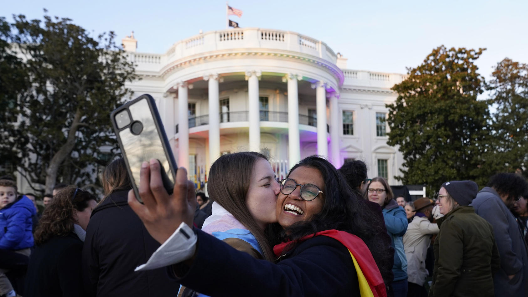 Aparna Shrivastava, right, takes a photo as her partner Shelby Teeter gives her a kiss, after President Joe Biden signed the Respect for Marriage Act, Tuesday, Dec. 13, 2022, on the South Lawn of the White House in Washington. (AP Photo/Andrew Harnik
