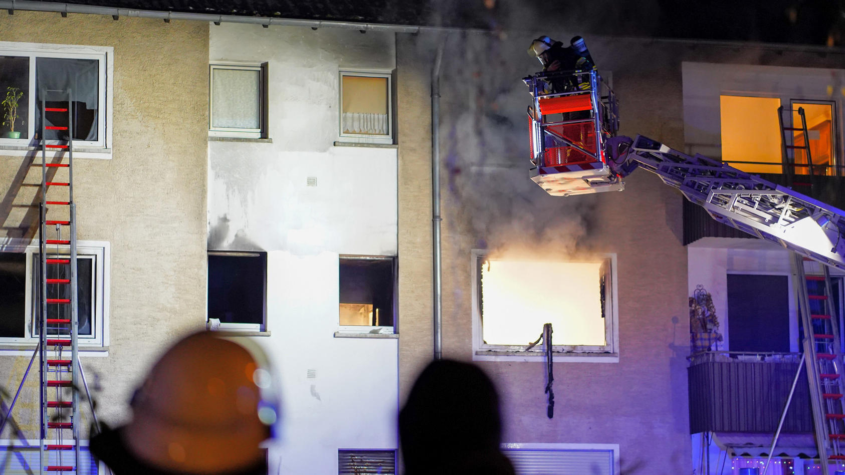 19.12.2022, Hessen, Wiesbaden: Feuerwehrleute mit Atemschutz löschen von einer Drehleiter aus den Brand in einem Haus. Bei einem Wohnungsbrand in Wiesbaden-Dotzheim ist ein Mann ums Leben gekommen. Der Bewohner konnte in der Nacht zu Montag zwar aus 