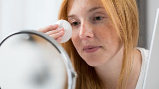 Junge rothaarige Frau entfernt ihr Augen-Make-up mit einem Wattepad