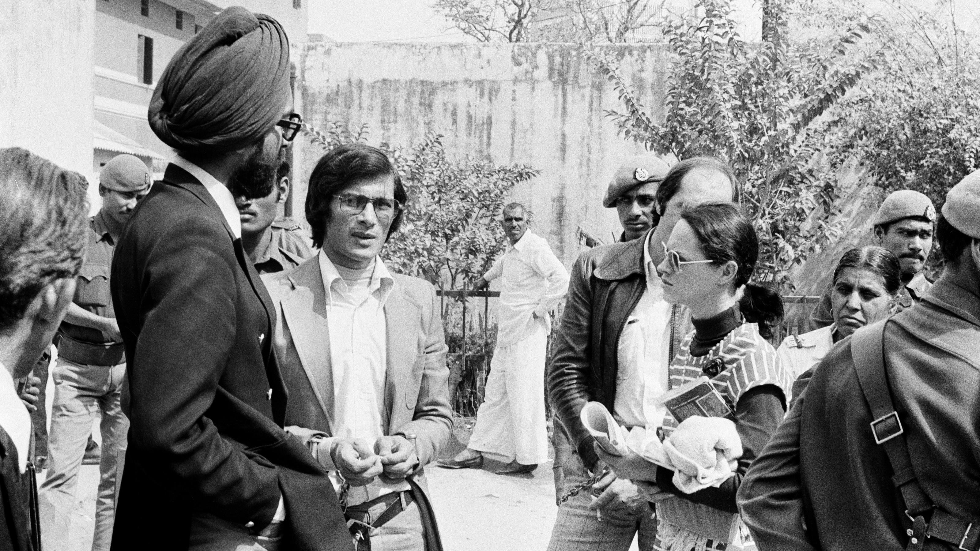 Charles Sobhraj, center, the alleged leader of an Asian murder ring, and his girlfriend Marie-Andrée Leclerc, in a striped dress, wait outside court during one of their appearances, in New Delhi, India , February 24, 1977. They are in preliminary court 