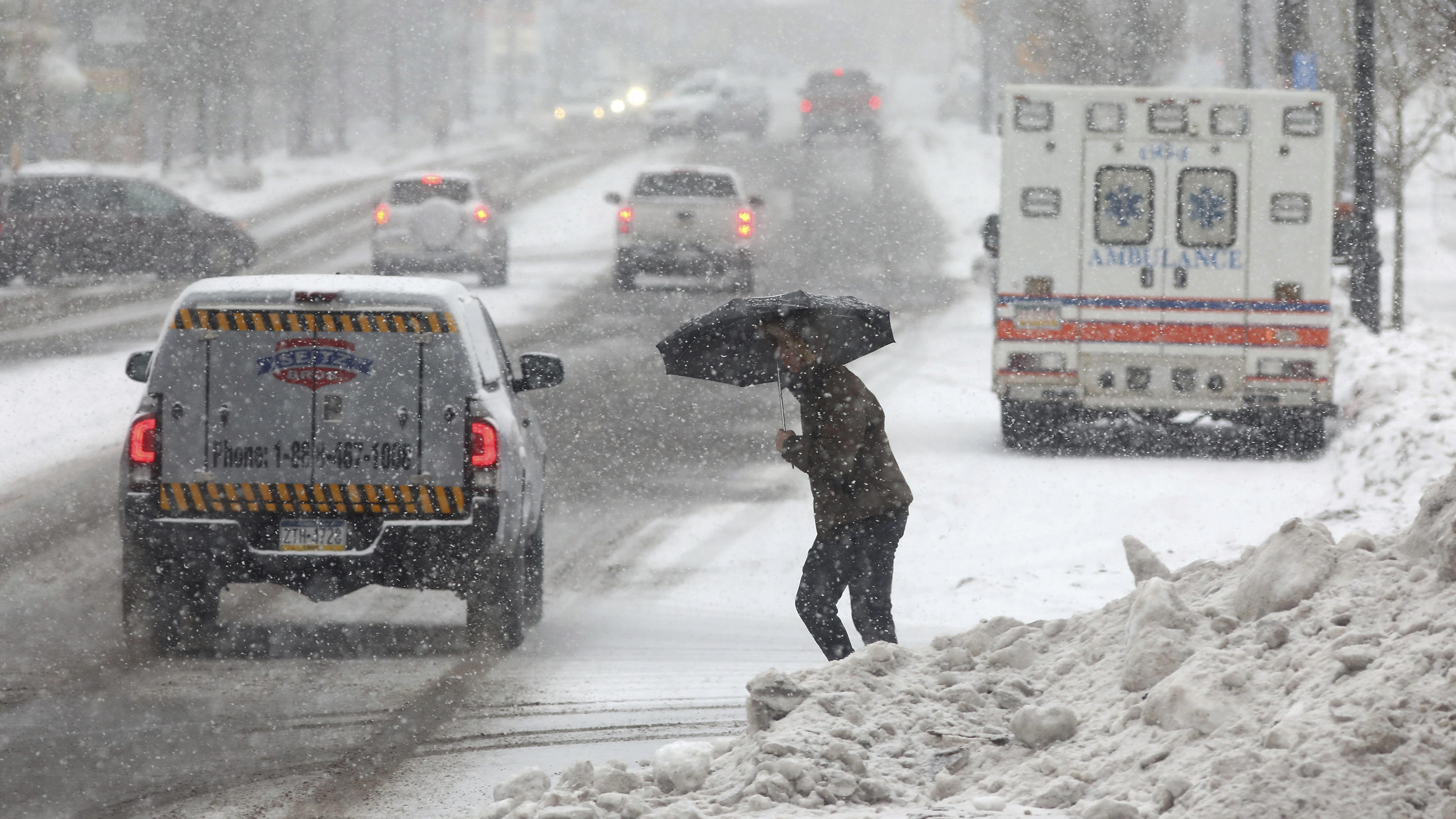 dpatopbilder - 22.12.2022, USA, Hazleton: Eine Person überquert eine Straße, während sie sich mit einem Regenschirm vor dem beginnenden Schneefall schützt. Ein arktisches Sturmtief bringt über die Weihnachtstage drastische Temperaturstürze und extrem