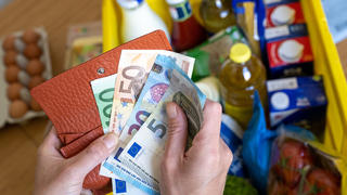 ARCHIV - 02.06.2022, Sachsen, Leipzig: Eine Einkaufskiste mit Lebensmitteln steht auf einem Küchentisch, während eine Frau Euro-Banknoten in den Händen hält. Sprunghaft gestiegene Preise belasten die Budgets der Menschen in Deutschland. Wie sich die Inflation im Dezember und im Schnitt des Gesamtjahres 2022 entwickelt hat, gibt das Statistische Bundesamt am Dienstagnachmittag in einer ersten Schätzung bekannt. (zu dpa: ««Hohe Inflation - Bundesamt gibt Daten fürs Gesamtjahr 2022 bekannt») Foto: Hendrik Schmidt/dpa +++ dpa-Bildfunk +++