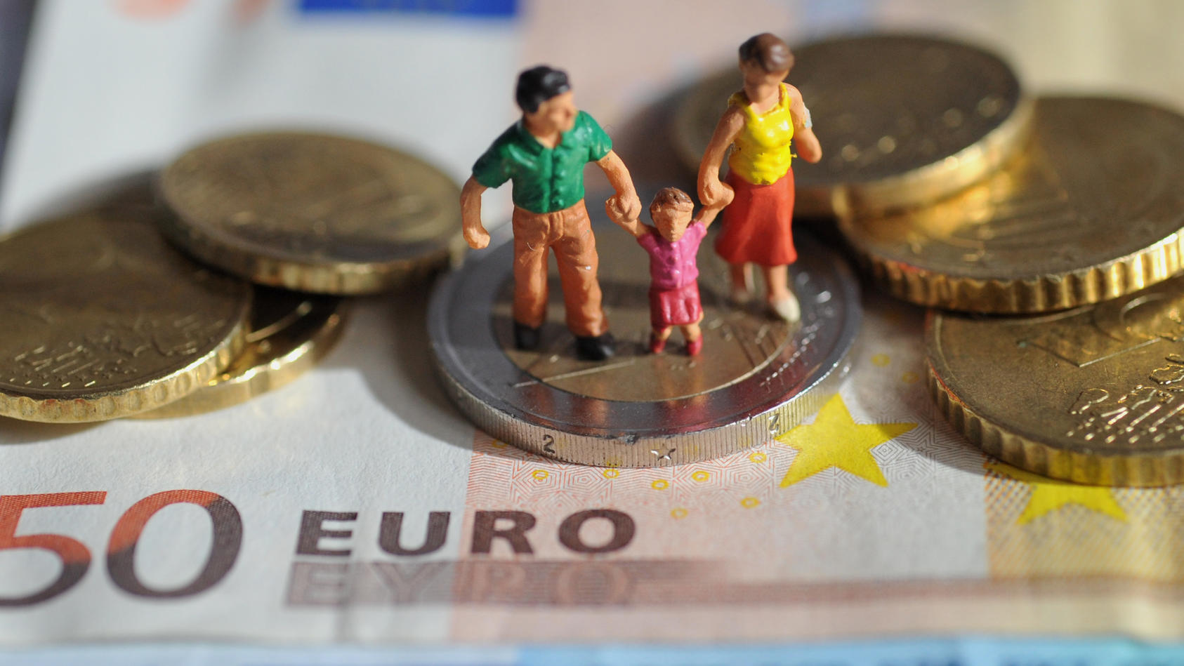 ILLUSTRATION - Ein Paar mit einem Kind steht auf einer Zwei-Euro-Münze, die auf einem 50-Euro-Schein liegt, aufgenommen am 16.02.2011. Foto: Andreas Gebert dpa/lby