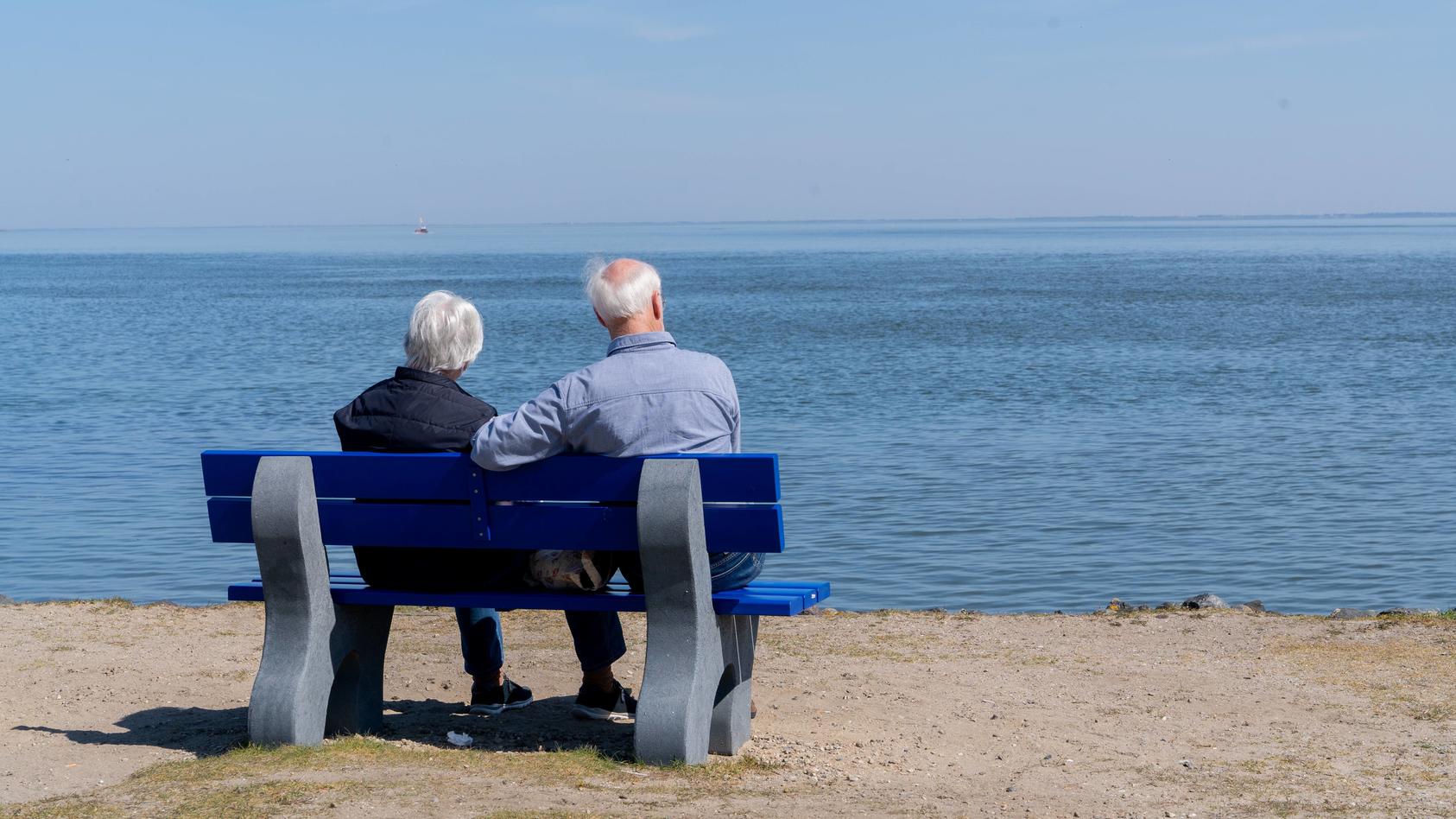 Zwei ältere Menschen sitzen in List auf der Insel Sylt auf einer Pank und schauen auf die Nordsee - Symbolfoto alte Frau alter Mann Rente Rentner Ruhestand Einsamkeit Zweisamkeit Parkbank am Wasser Meer altern älter werden Absicherung Sicherheit Wohl