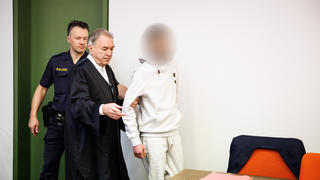 Ein wegen Totschlags angeklagter Mann (r), der seine fünf Wochen alte Tochter in Oberammergau umgebracht haben soll, wird zu Prozessbeginn in einen Gerichtssaal vom Landgericht in München geführt. In der Mitte steht sein Rechtsanwalt Sewarion Kirkita