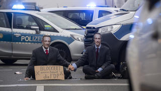 Aktivisten der Gruppe "Letzte Generation" saßen im November auf einer Kreuzung an der Landsberger Allee in Berlin und trugen Masken, die Bundesfinanzminister Lindner zeigten. Aufgrund der Blockade kam es zu erheblichen Verkehrsbehinderungen.