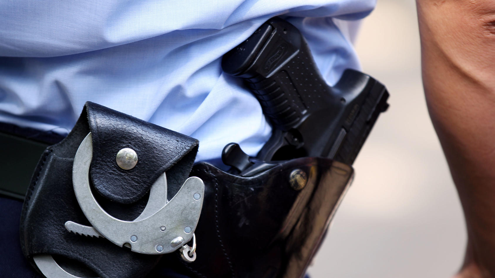ARCHIV - 28.06.2011, Nordrhein-Westfalen, Köln: Ein Polizist trägt Handschellen und seine Dienstwaffe bei sich. Im Jahr 2022 sind in Sachsen zwei Menschen nach Schüssen aus Polizeiwaffen ums Leben gekommen. (zu dpa «Zwei Menschen 2022 nach Schusswaff