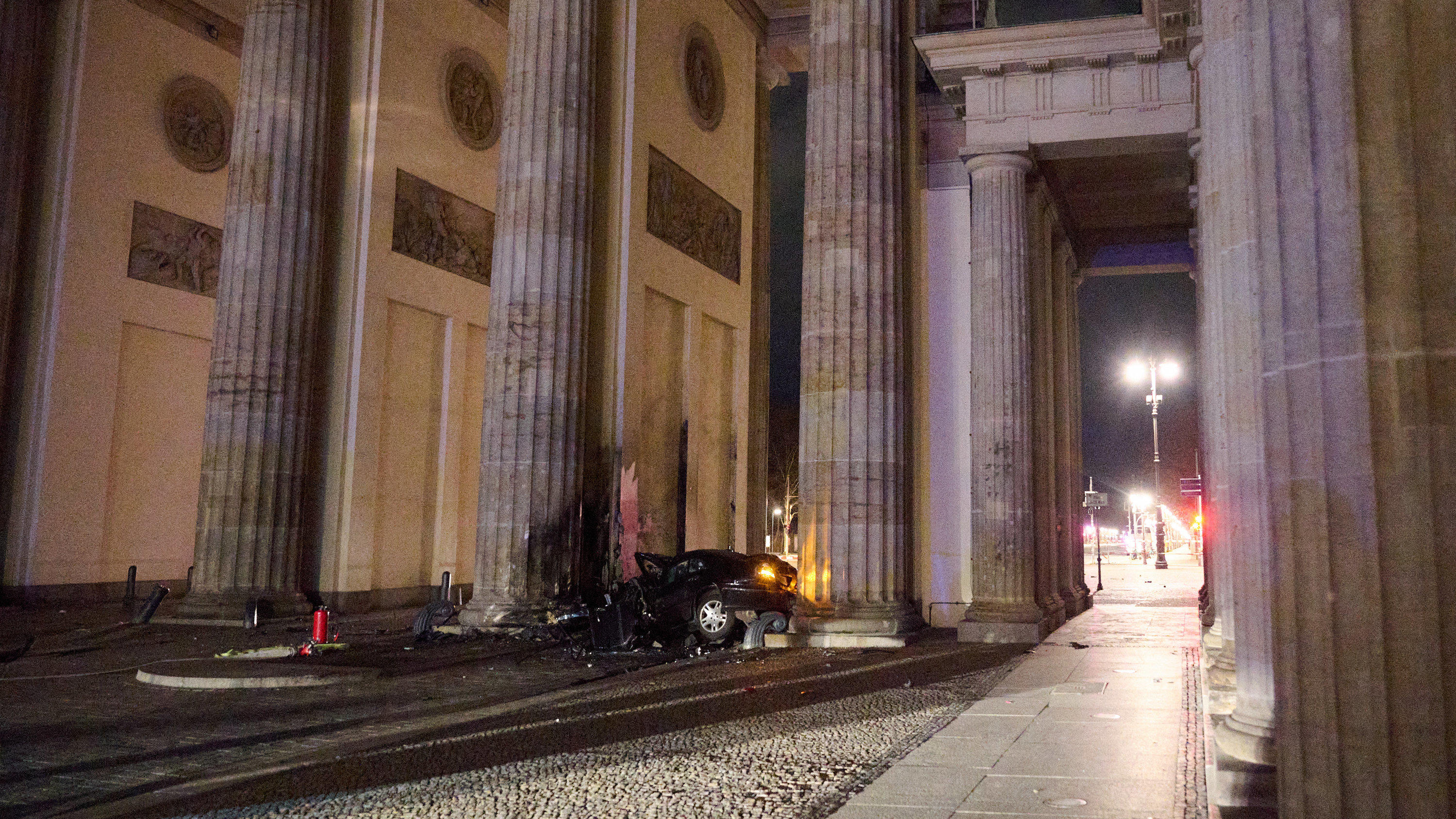 16.01.2023, Berlin: Ein zerstörter PKW liegt zwischen zwei Säulen des Brandenburger Tors. Ein Auto ist gegen eine Säule des Brandenburger Tors in Berlin gefahren. In dem Wagen hätten Feuerwehrleute einen toten Mann gefunden, sagte ein Polizeisprecher
