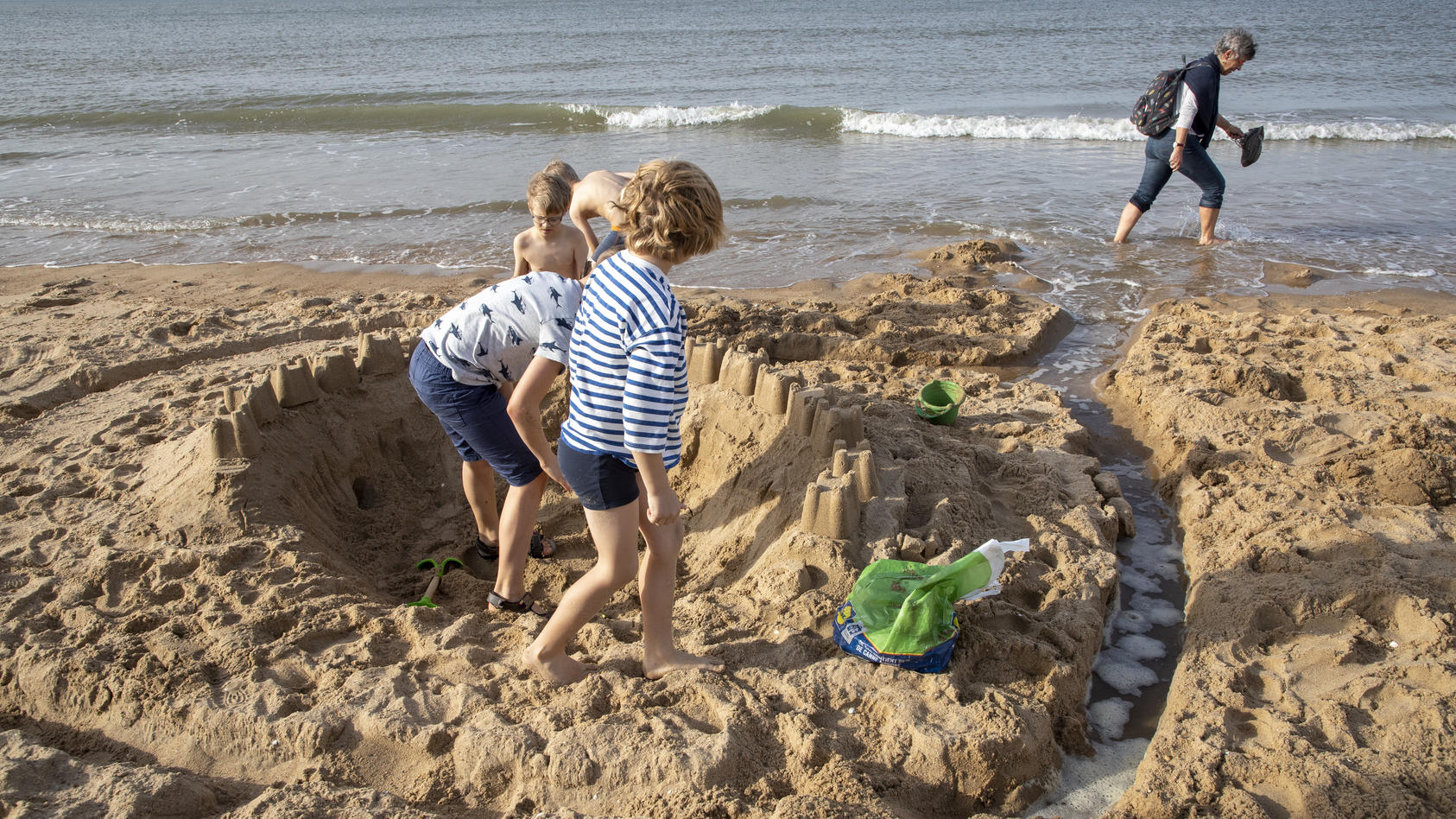 Kinder buddeln im Sand und bauen Sandburgen am Strand.
