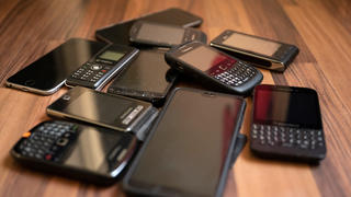 Ungenutzte alte Handys liegen auf dem Boden.