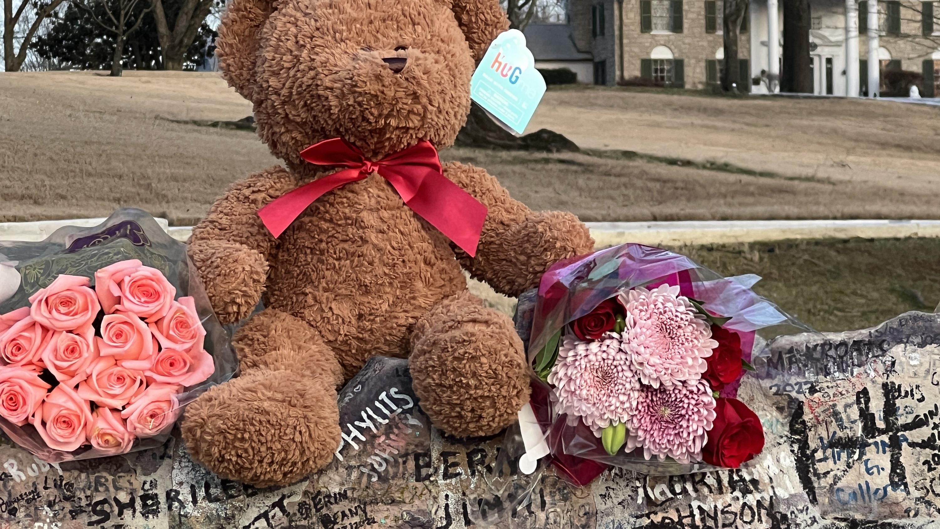 14.01.2023, USA, Memphis: Musikfans haben nach dem Tod der  Sängerin Lisa Marie Presley vor dem Anwesen Graceland Blumensträuße und einen Teddy abgelegt. Lisa Marie lebte während ihrer frühen Kindheit in Graceland und kehrte häufig in die Villa zurüc