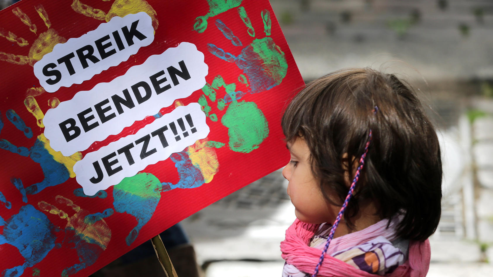 ARCHIV - Ein kleines Mädchen hält am 26.05.2015 in Hamburg bei der Kundgebung des Landeselternausschuss (LEA) Hamburg ein Plakat mit der Aufschrift «Streik Beenden Jetzt» in den Händen.  Foto: Axel Heimken/dpa (zu dpa "Schlichtung im Kita-Tarifkonfli